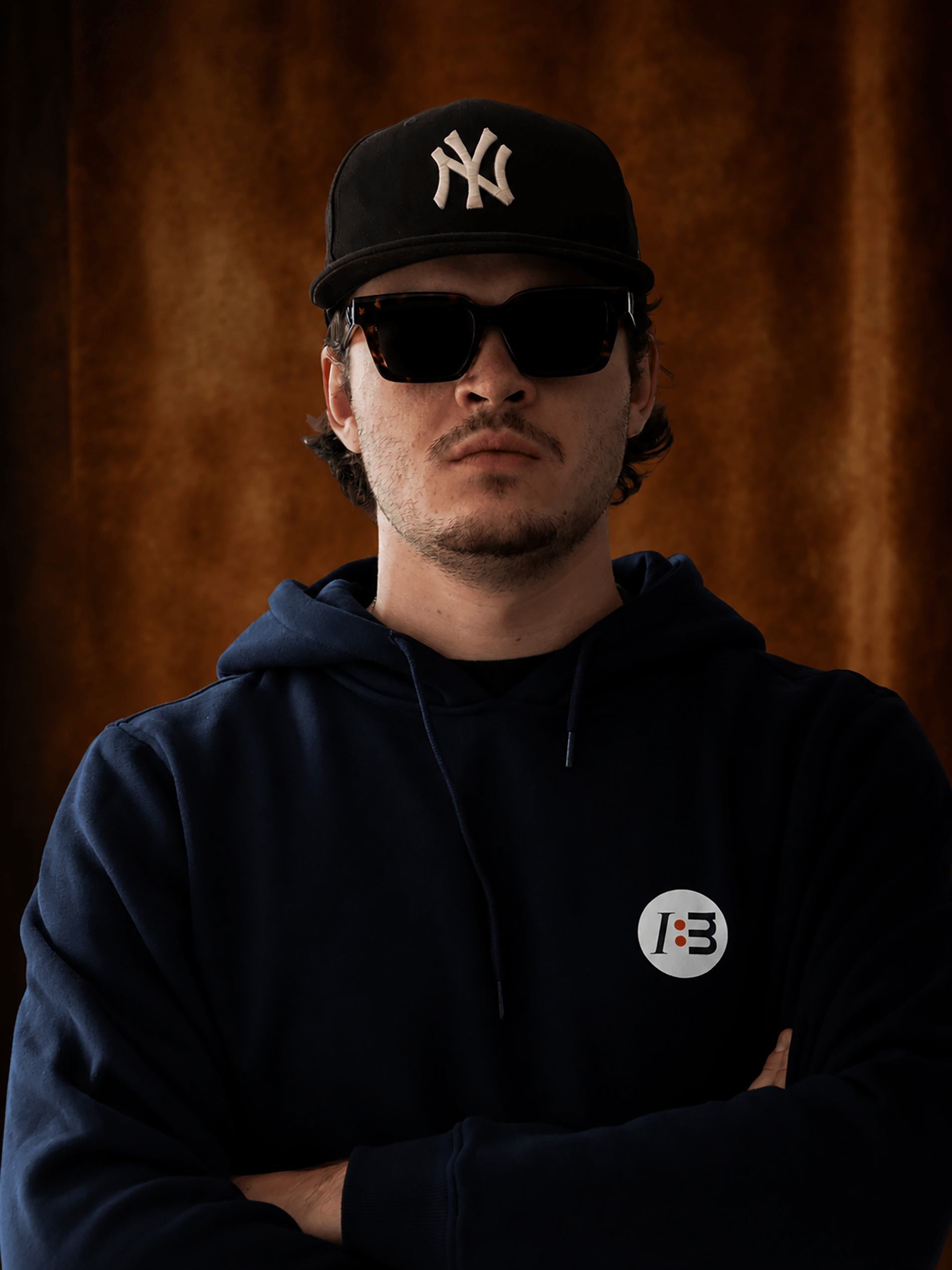 Junger Mann mit dunklen Haaren, Hoodie und Yankees-Kappe – Marketingprofi.